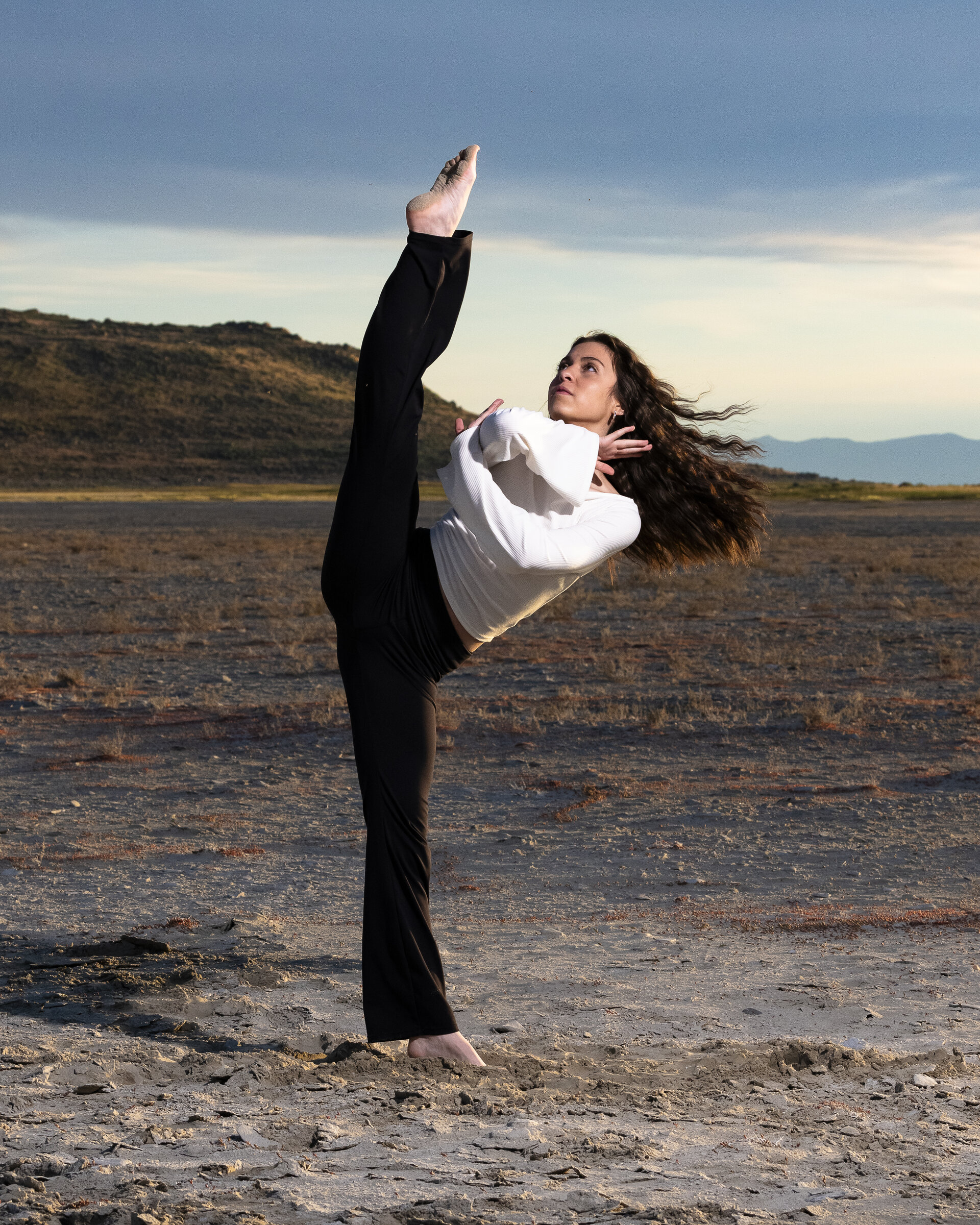 Maya performing a standing split in the desert
